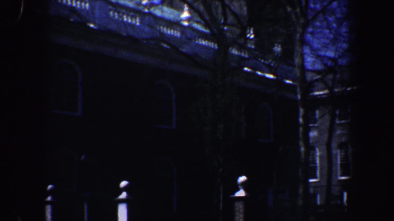 Dark brick building partly hidden by bare trees and shadow.