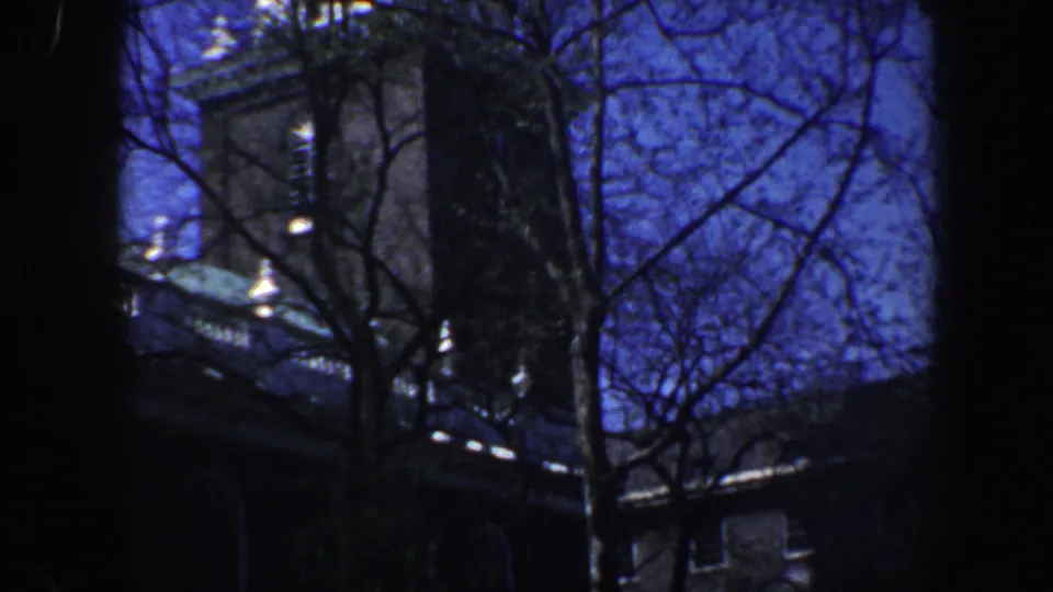 1962 Philadelphia 8mm frame showing bare branches crossing a historic-looking building facade and tower against deep blue sky.