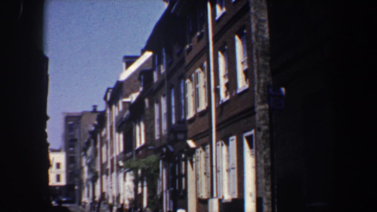 Brick row houses and street lamps seen from a low, shadowed street view.