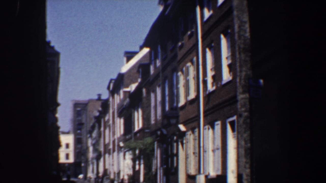 Similar street view of brown row buildings and white windows under bright sky.