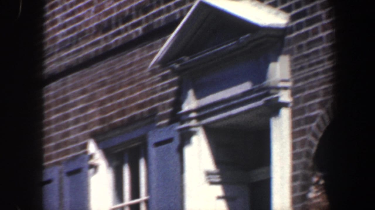 Brick apartment facade with blue shutters, white trim, and an a-frame roof detail.