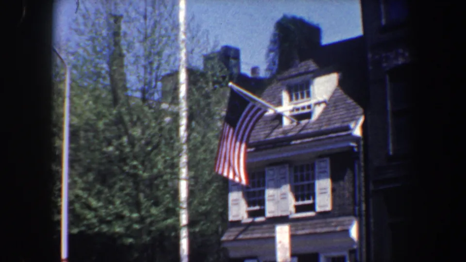 Final 1962 Philadelphia frame of the brick residence and Betsy Ross-style flag, with 8mm edge darkness visible.