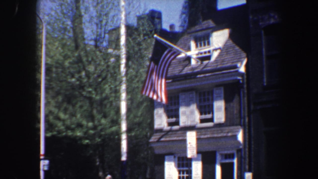 Brick building with white shutters and an American flag beside trees.