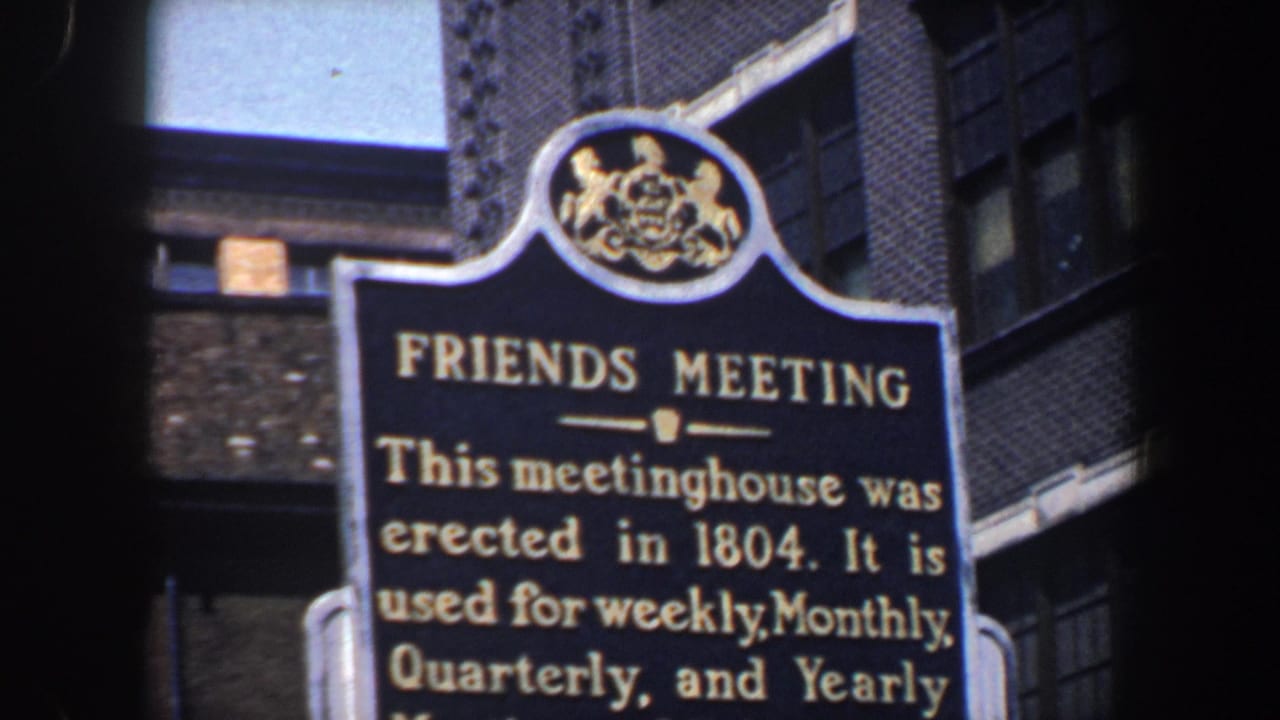 Close view of a Friends Meeting historical marker beside brick buildings.