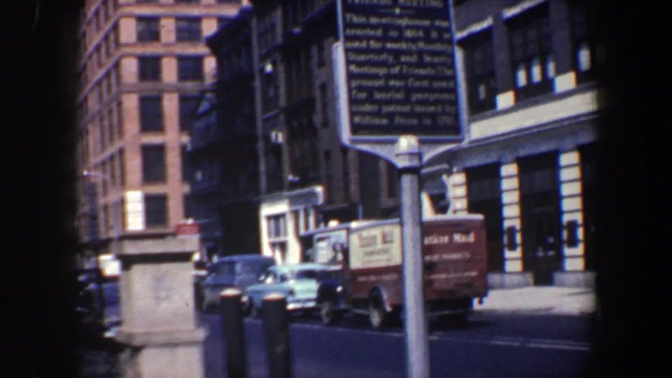 1962 Philadelphia street scene showing the Friends Meeting marker, parked mid-century cars, a brown delivery truck, and commercial buildings.