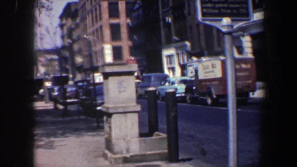 Wide 1962 Philadelphia view of the Friends Meeting marker beside cars, a delivery truck, sidewalk posts, and a stone street fixture.