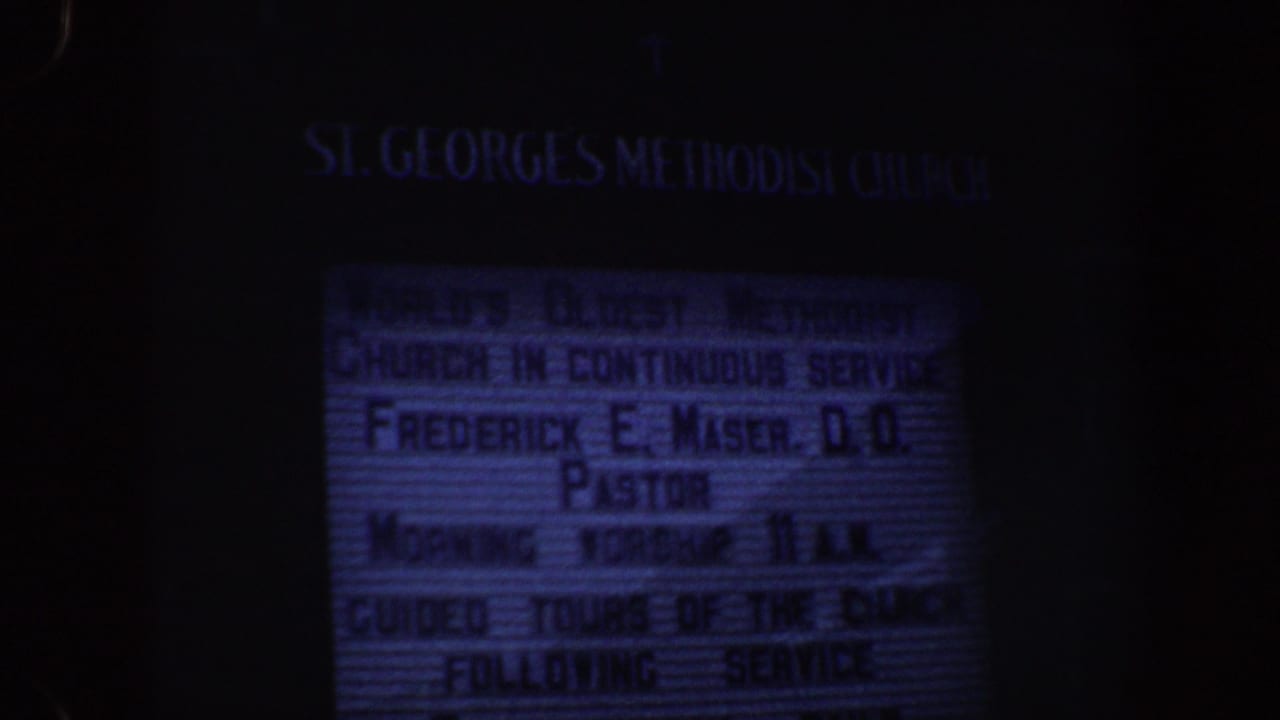 Dim blue-tinted church letterboard for St. George's Methodist Church in darkness.