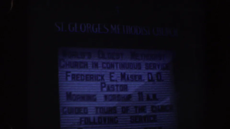 1962 Philadelphia 8mm frame showing a dark, blue-tinted St. George's Methodist Church marquee with pastor and service details.