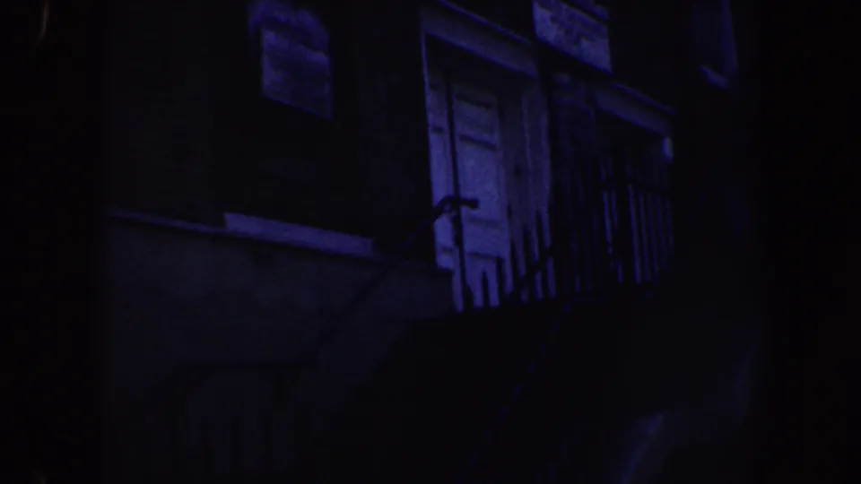 1962 Philadelphia nighttime frame with a white upper door, nearby window, balcony railing, and deep blue-purple exposure.