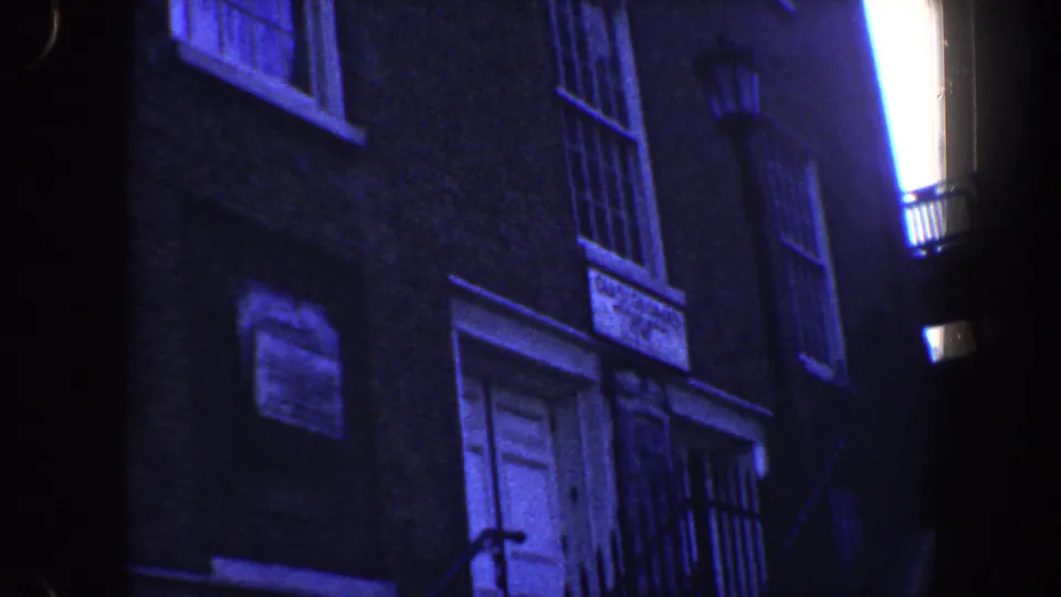 1962 Philadelphia frame showing the brick building more clearly, with white doors, barred windows, iron railings, and a bright side light.
