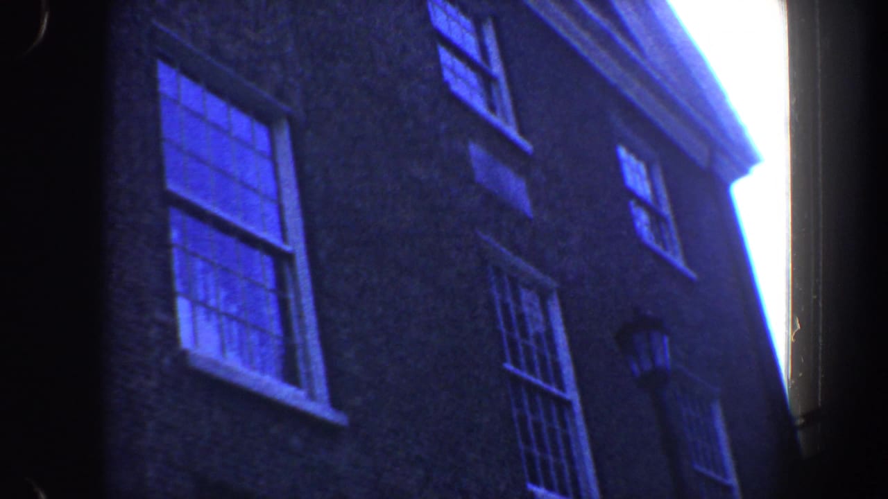 Tall brick building facade with several windows seen from below.