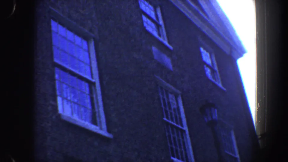 Low-angle 1962 Philadelphia exterior view of a brick historic building, with blue-tinted windows and a narrow bright sky edge.