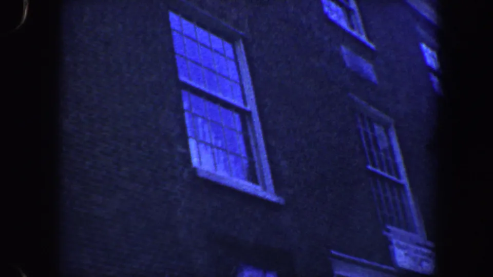 Handheld 8mm frame of the Philadelphia brick building exterior, focusing on window rows and darkened facade texture.