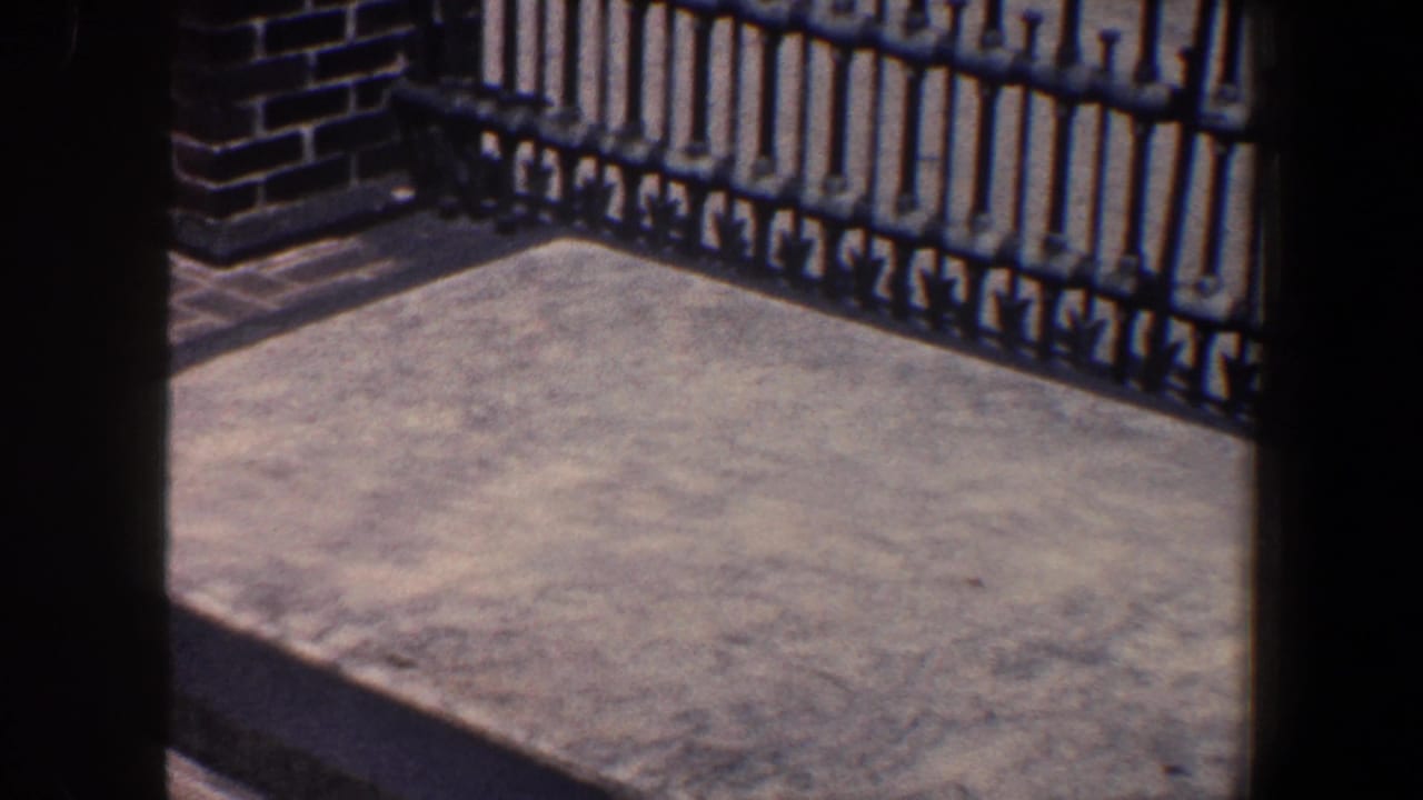 Concrete platform behind a black iron gate with brickwork at the left edge.