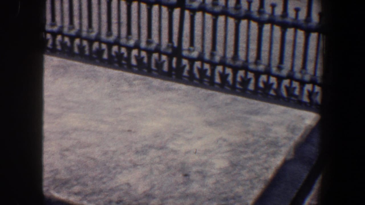 Concrete platform and black iron railing seen through dark vertical frame edges.