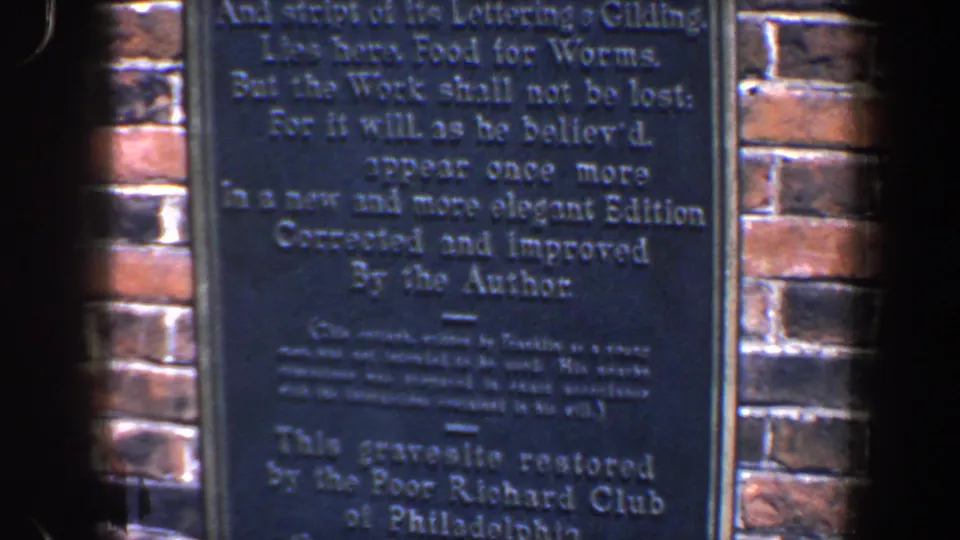 Lower section of the Franklin plaque in Philadelphia, showing restoration wording beneath the poem on grainy 8mm film.