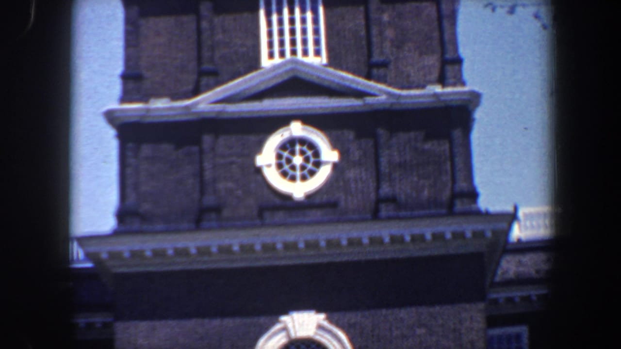 Dark brick clock tower facade with white trim and blue sky.