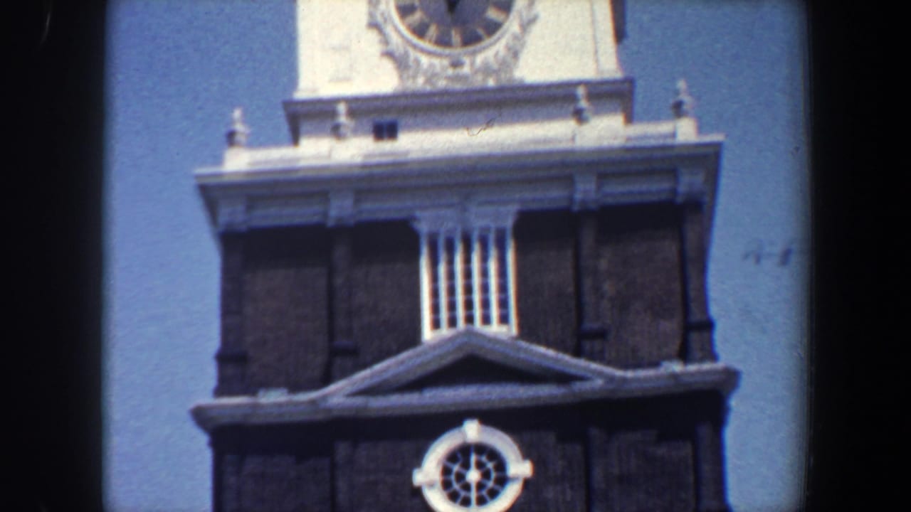 1962 Philadelphia frame showing a historic tower section with a round clock face, white cornice, louvered opening, and dark brickwork.