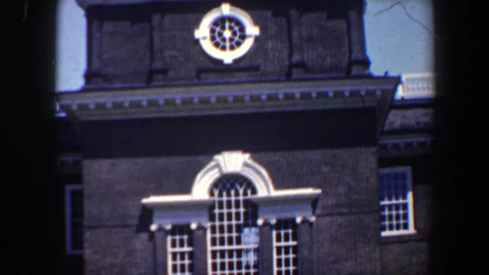 1962 Philadelphia home-movie frame focused on the dark facade, circular window, and arched window with white trim.