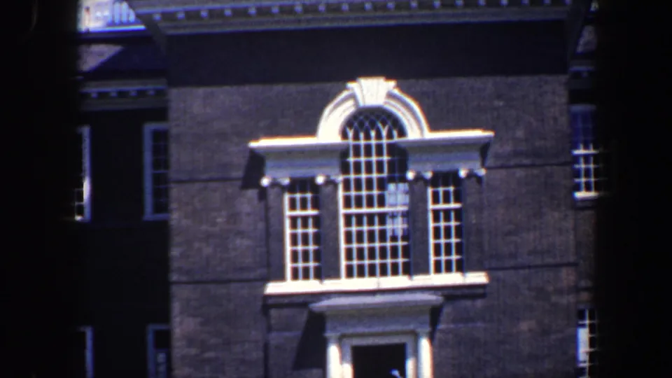 1962 Philadelphia frame showing a dark masonry facade with a tall arched window and white architectural trim.