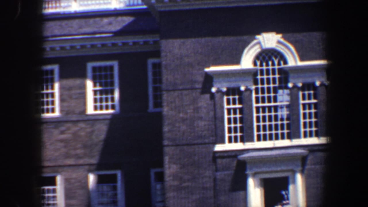 Brick building facade with white-trimmed windows and a large arched central window.
