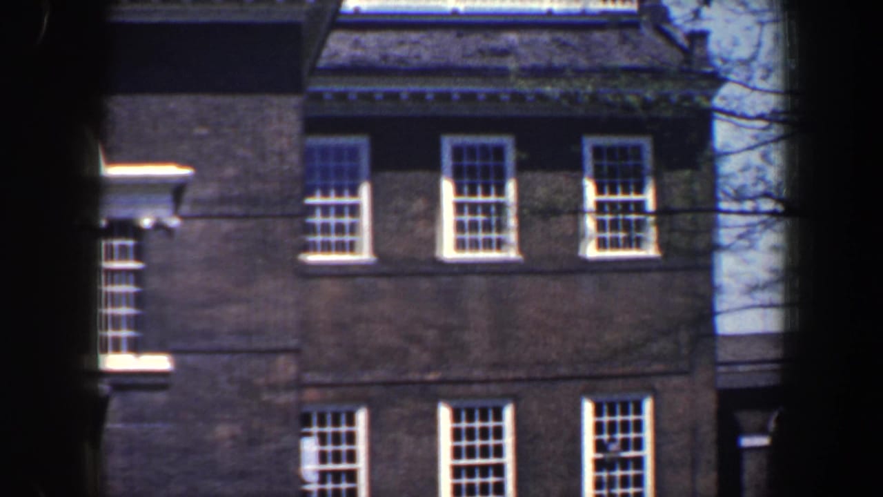 Close view of a brick building with white-trimmed windows and dark film edges.