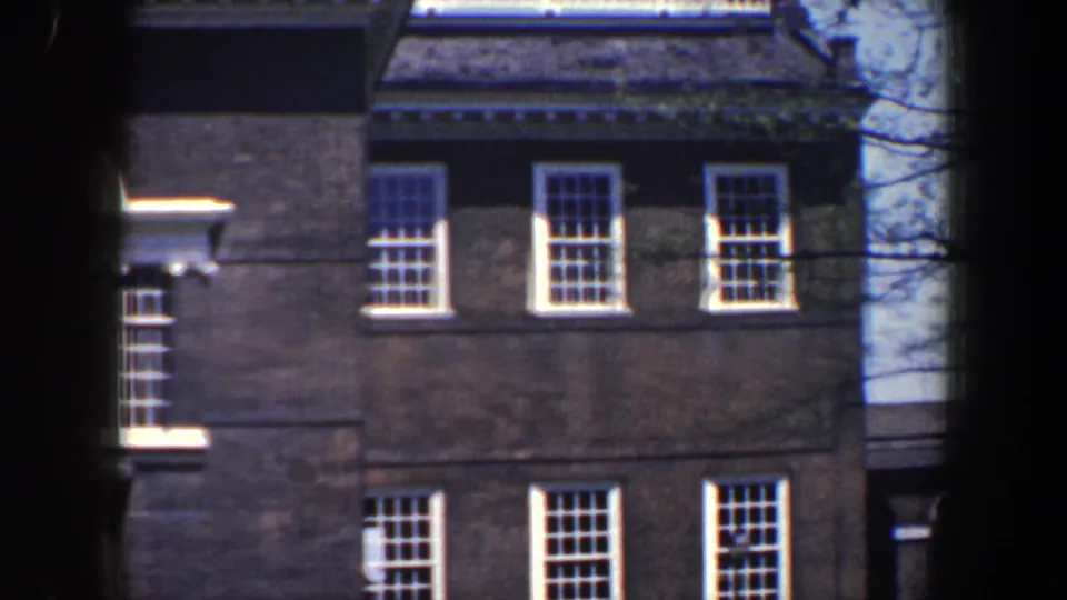 Brick building facade in Philadelphia, 1962, with white-trimmed sash windows and soft 8mm home-movie exposure.