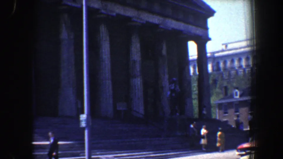1962 Philadelphia view of pedestrians by the steps of a large columned building, with a partial period car at right.
