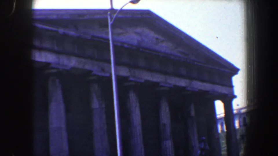 1962 Philadelphia frame emphasizing the pediment and column tops of a monumental classical building from street level.