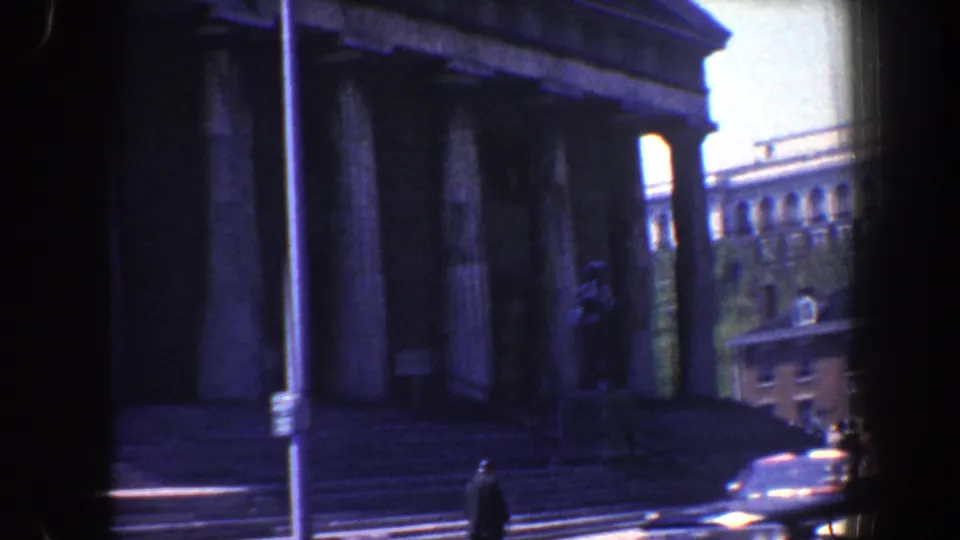 A 1962 Philadelphia street view shows the columned building, steps, a pedestrian near the curb, and multi-story buildings in the background.