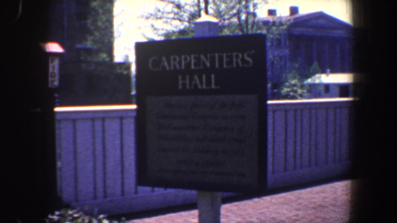 Carpenters' Hall sign stands beside a brick walkway and fence.