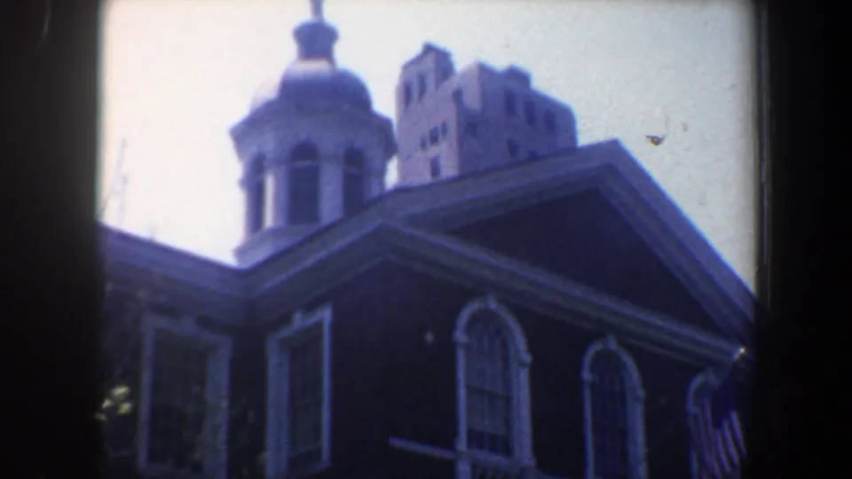 1962 Philadelphia home-movie view of a domed roofline, arched windows, an American flag, and a taller building in the background.