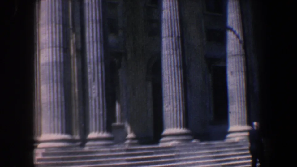 1962 Philadelphia 8mm frame showing the columned entrance and steps of a historic public building, with a person near the right edge.