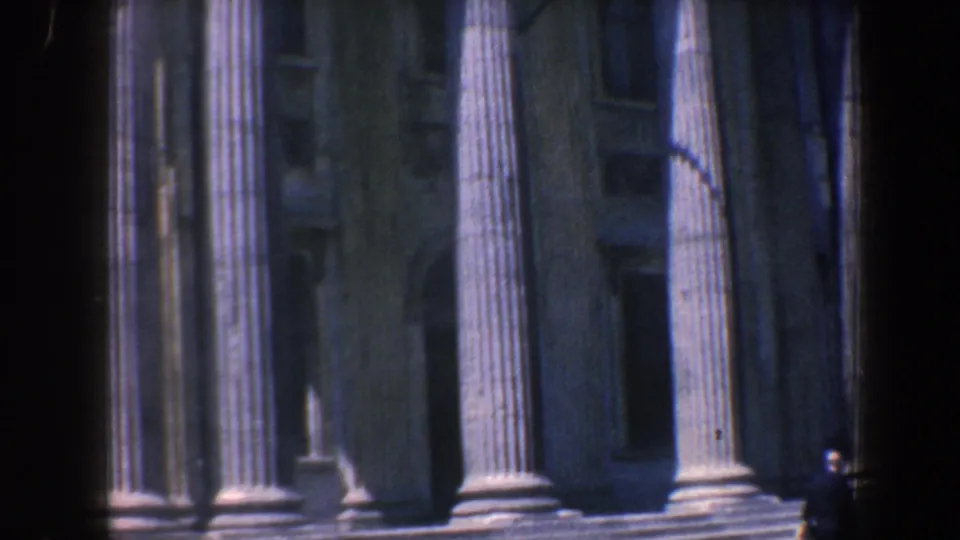 1962 Philadelphia home-movie frame showing a columned stone civic-looking facade with broad steps and a small pedestrian near the base.