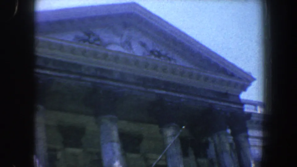 Vintage 8mm frame of a Philadelphia classical building, with pediment, cornice, and columns viewed from street level.