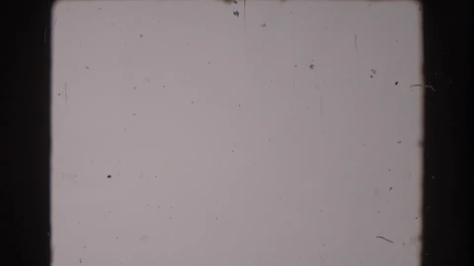 Blank 1962 8mm frame area with a light field, dark vertical border, scattered dust, and faint surface scratches.