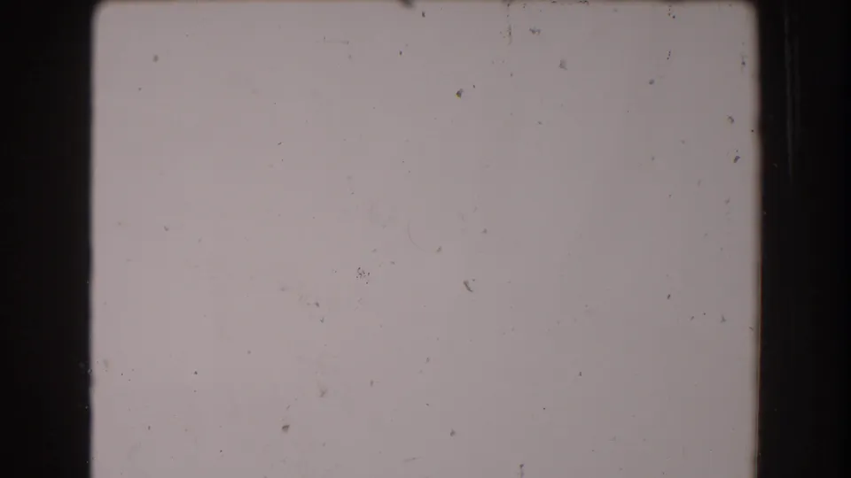 Lower blank 8mm frame from the 1962 North Hollywood footage, with pale film tone, dark border, dust, and faint scratches.