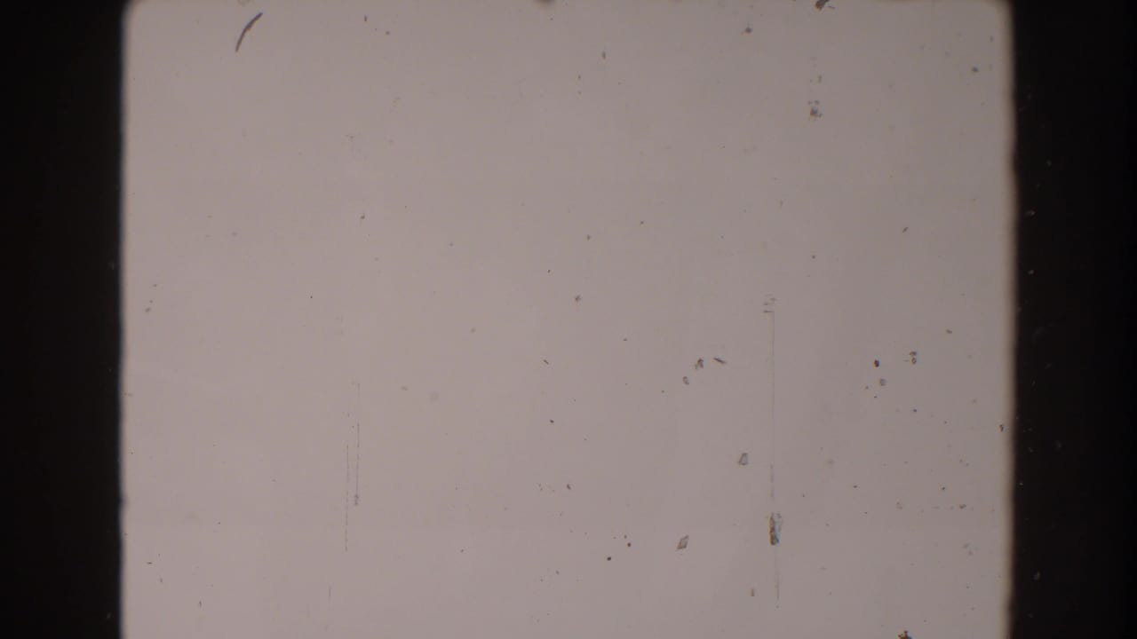 Blank-looking 8mm frame from the supplied 1962 North Hollywood clip, showing film gate edges, dust, and faint scratches.