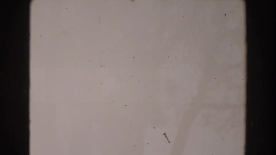 A pale 8mm frame from the supplied 1962 North Hollywood clip, showing gate edges, dirt, scratches, and uneven exposure.