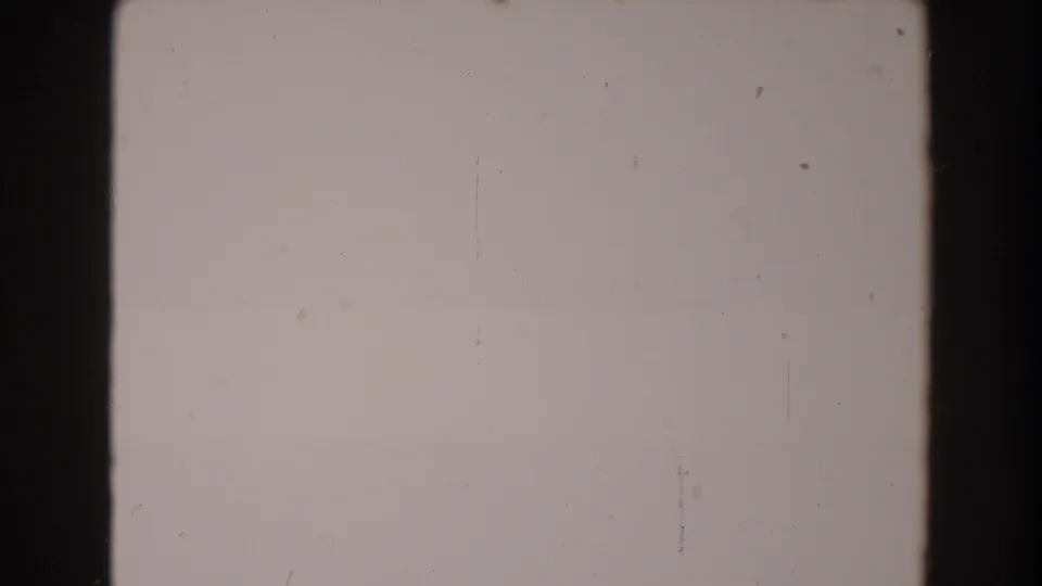 Blank-looking 8mm frame from the supplied 1962 North Hollywood clip, showing a dark film edge, dust specks, and faint scratches.