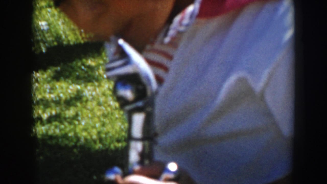 Close view of a boy in a striped shirt holding a small mechanical object.