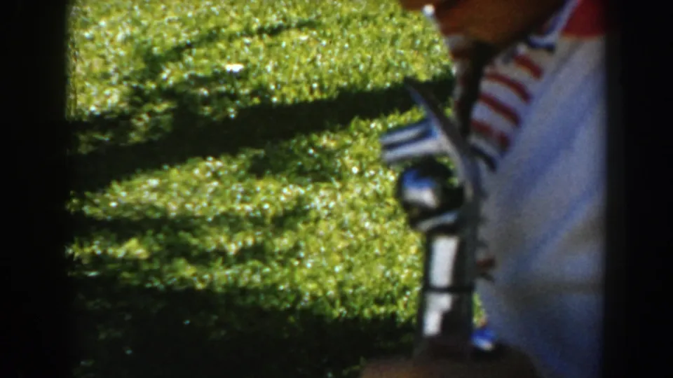 The final frame keeps the boy and small handheld object in close view, with bright green lawn and hedge filling the background.