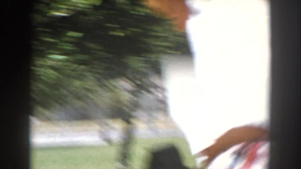 Bright 1962 North Hollywood home-movie frame with a partial figure, greenery, and overexposed sunlit edge.