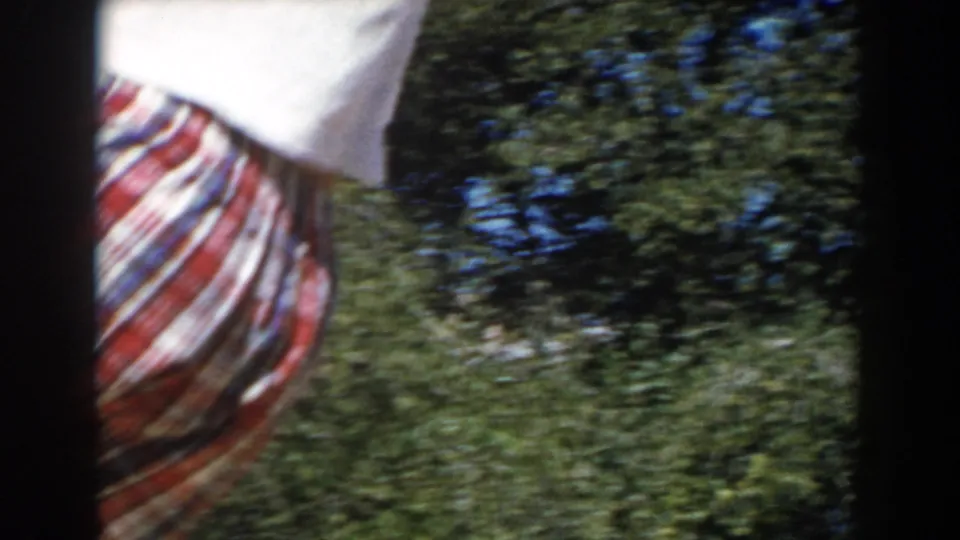 A partial view of the child in plaid clothing appears beside the tree, blurred by movement in the 1962 North Hollywood 8mm footage.