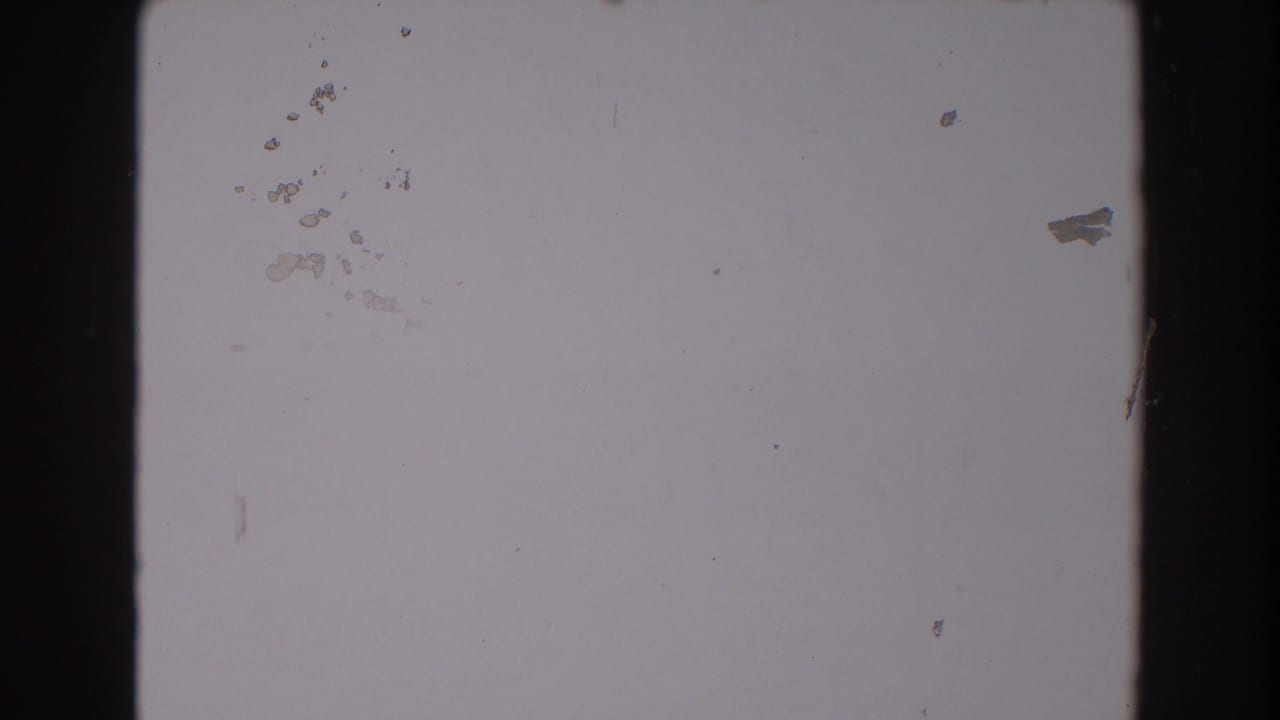 1962 North Hollywood 8mm frame showing an overexposed blank area with black film edge, dust, and small scratches.