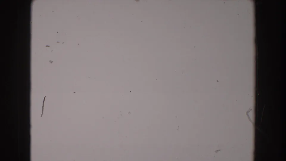1962 North Hollywood 8mm frame showing pale blank film with a black edge, scratch marks, dust, and uneven exposure.