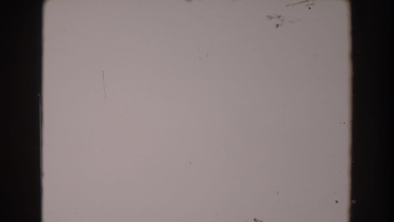 1962 North Hollywood 8mm home-movie frame showing blank pale film area with dark edges, dust specks, and light scratches.