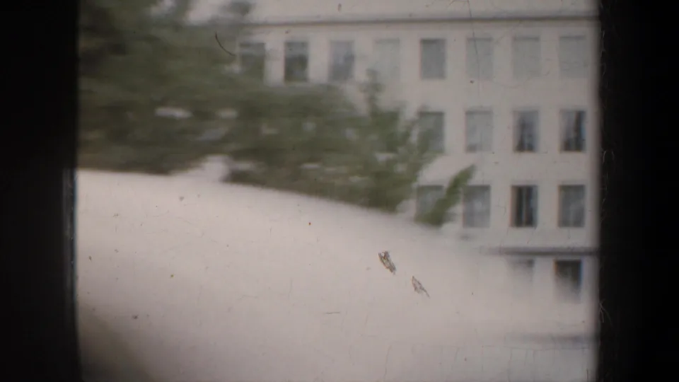 A moving 1957 San Francisco home-movie view catches a white curved architectural form with trees and a pale building behind it.