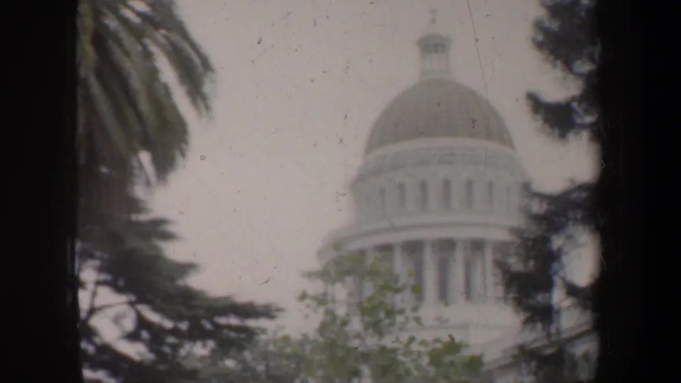 The California State Capitol dome and columns are visible through trees in a soft 8mm home-movie frame.