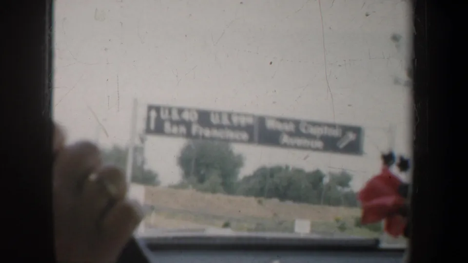 1957 California highway approach seen from a car interior, with overhead signs for San Francisco and West Capitol Avenue partly visible.